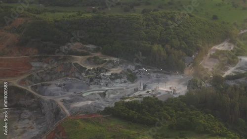 Aerial flying by mining excavation site around green forest
