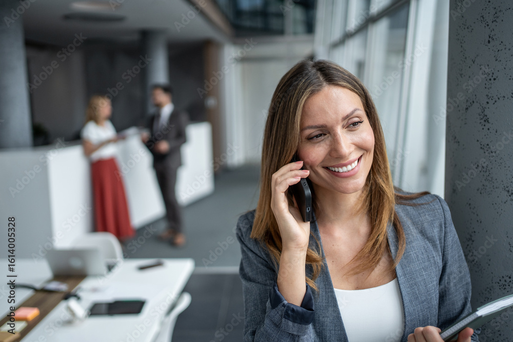 Businesswoman smiling while talking on phone in modern office Businesswoman smiling while talking on phone in modern office