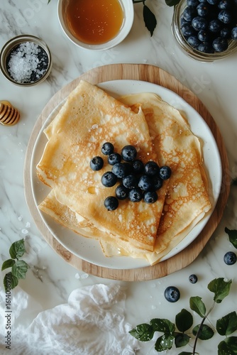 Freshly Made Crepes With Blueberries and Honey on a Wooden Plate