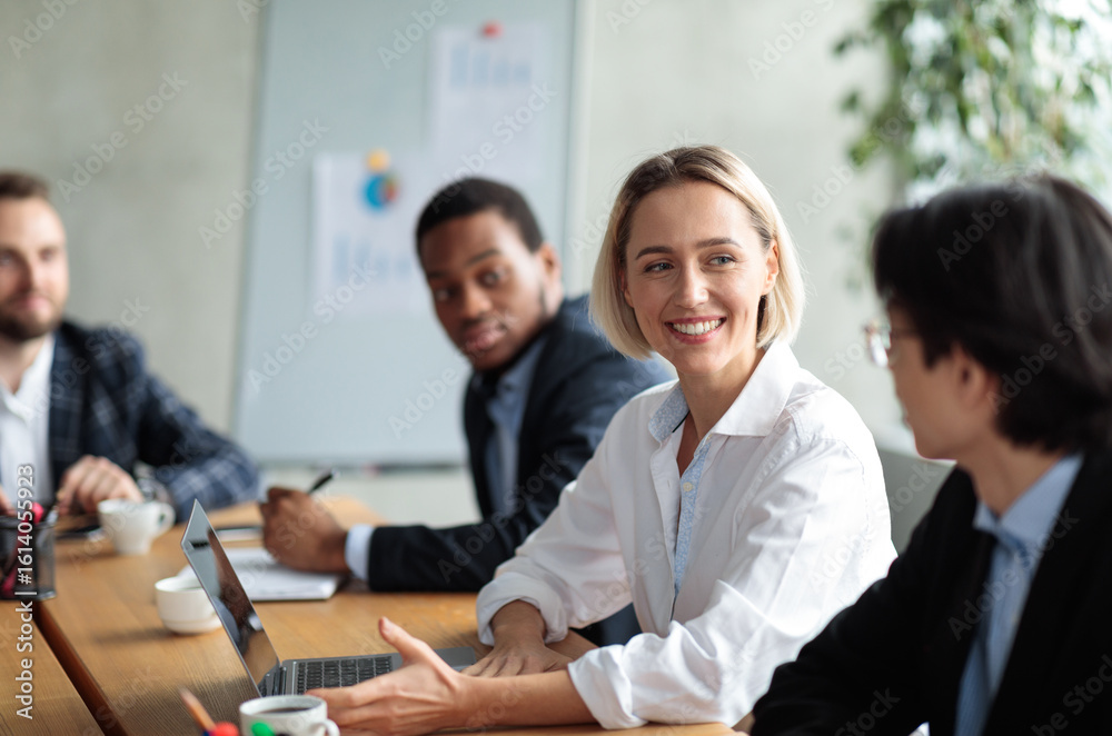 Successful Businesswoman On Corporate Meeting Smiling To Asian Businessman Colleague Discussing Business Project Sitting At Desk In Modern Office. Business Negotiation, Comunication, Networking Successful Businesswoman On Corporate Meeting Smiling To Asian Businessman Colleague Discussing Business Project Sitting At Desk In Modern Office. Business Negotiation, Comunication, Networking