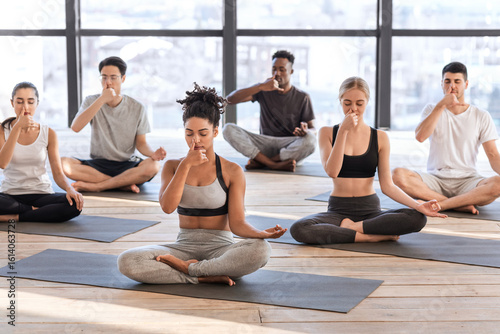 Tableau sur toile Young men and women in yoga studio practicing alternate nostril breathing exerci