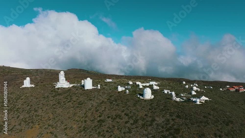 Drone shot of Teide Observatory above the clouds on Mount Izaña, Tenerife, with volcanic landscape under clear blue skies