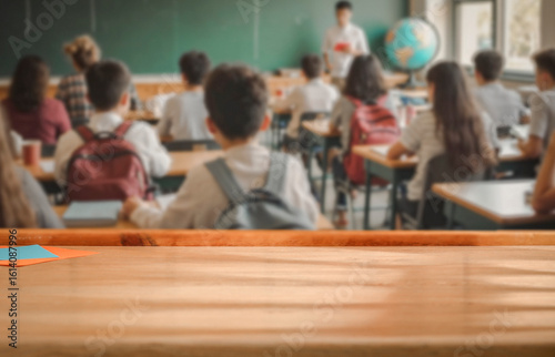 School desk with blurred students and teacher in classroom background. School-related atmosphere of learning, back-to-school excitement, and education in progress.