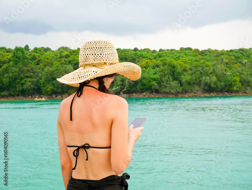 Woman with sunburned back using mobile phone
