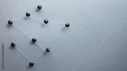 metal tacks attached with thread to a sheet representing a communication network and a dark background