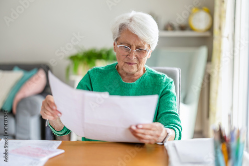Senior woman sitting in the living room and doing paperwork
