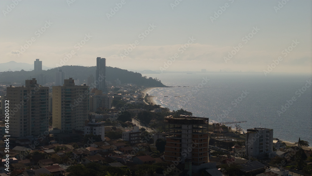 Obraz premium Coastal cityscape of Penha at dusk with high-rise buildings and shimmering ocean in Santa Catarina, Brazil.