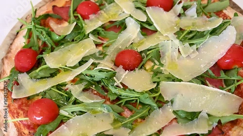Pizza served on a plate in a restaurant. Capricciosa pizza with cheese, salami, mushrooms, arugula and tomatoes.