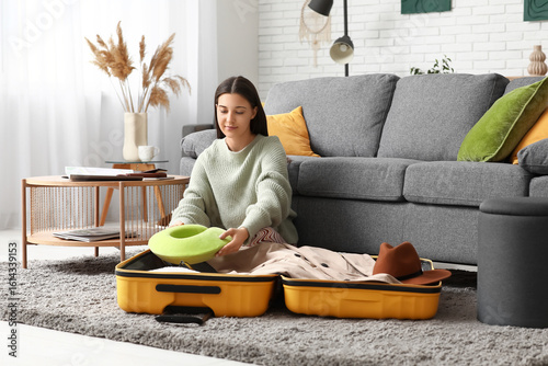 Young woman packing pillow ...