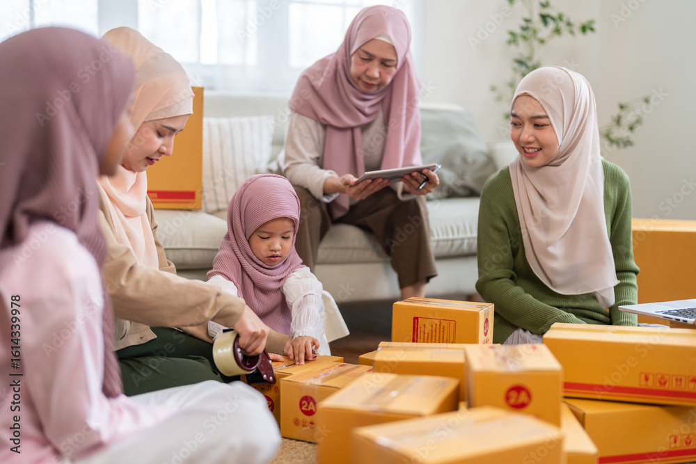 Fototapeta premium Muslim big family working together on online business packing parcels for shipping using laptop at home, halal brand startup teamwork, delivery, e-commerce with family and SME, muslim entrepreneurship