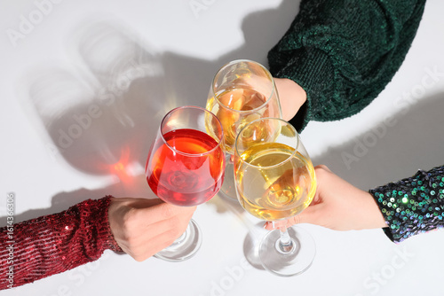 Female hands clinking glasses of wine on white background