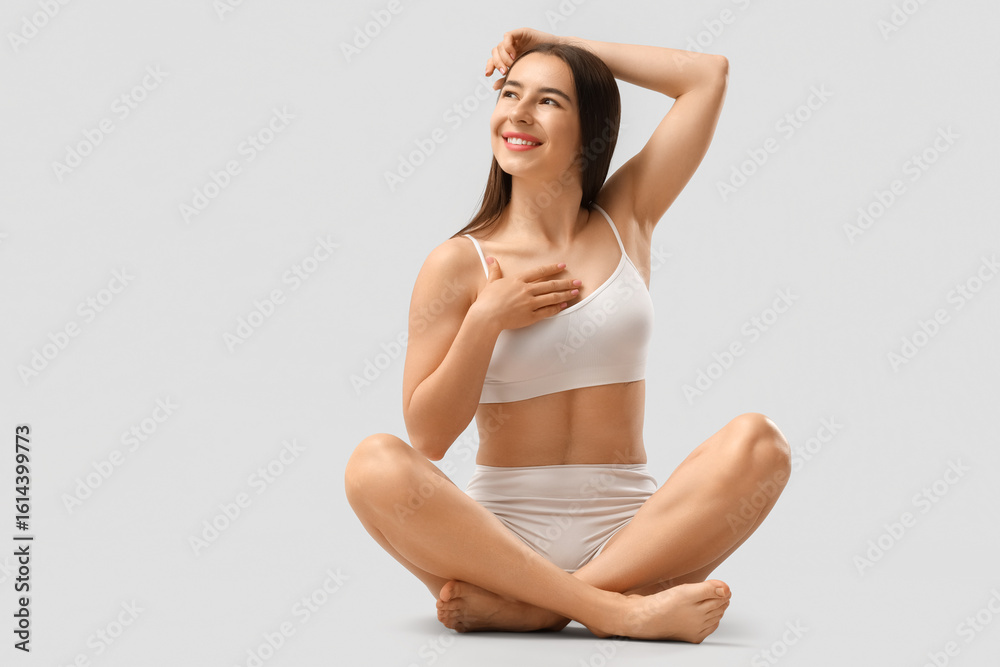 Obraz premium Happy young woman in stylish underwear sitting on white background