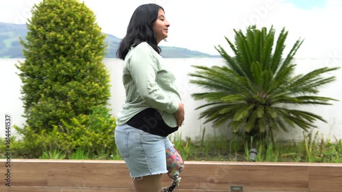 Pregnant woman with prosthetic leg walking in garden