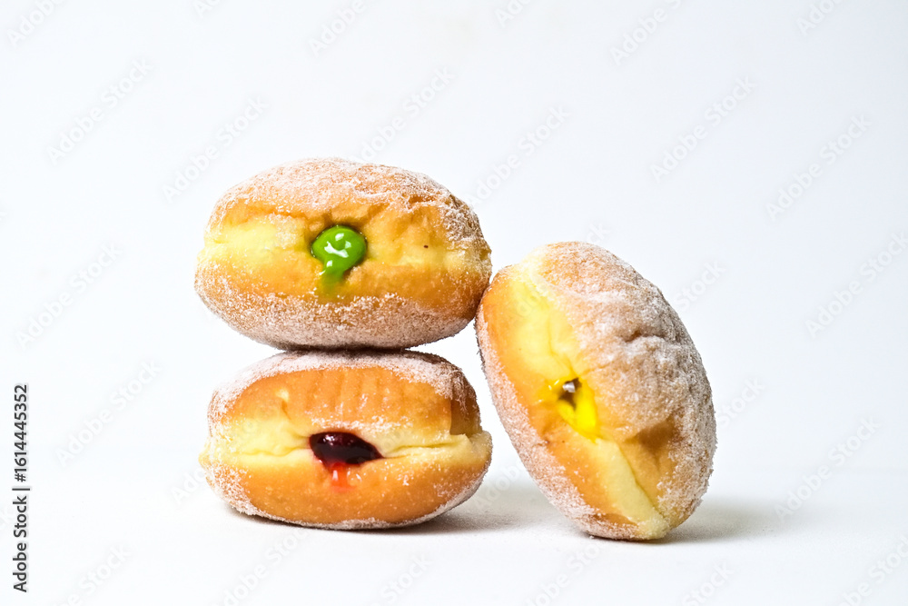 Side view of three bomboloni doughnut with strawberry, pineapple and matcha filling isolated on white background. clipping path. homemade. Italian stuffed donuts. close up. stack. pile. Side view of three bomboloni doughnut with strawberry, pineapple and matcha filling isolated on white background. clipping path. homemade. Italian stuffed donuts. close up. stack. pile.