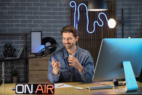 Smiling male podcaster reco...