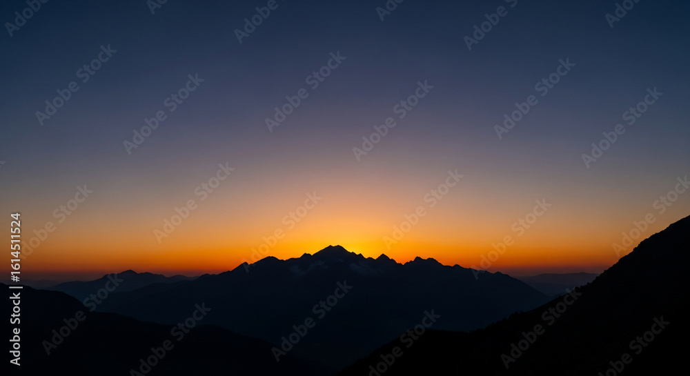 Obraz premium Vibrant Mountain Silhouette at Sunset: Golden Hour Peaks Against Twilight Sky