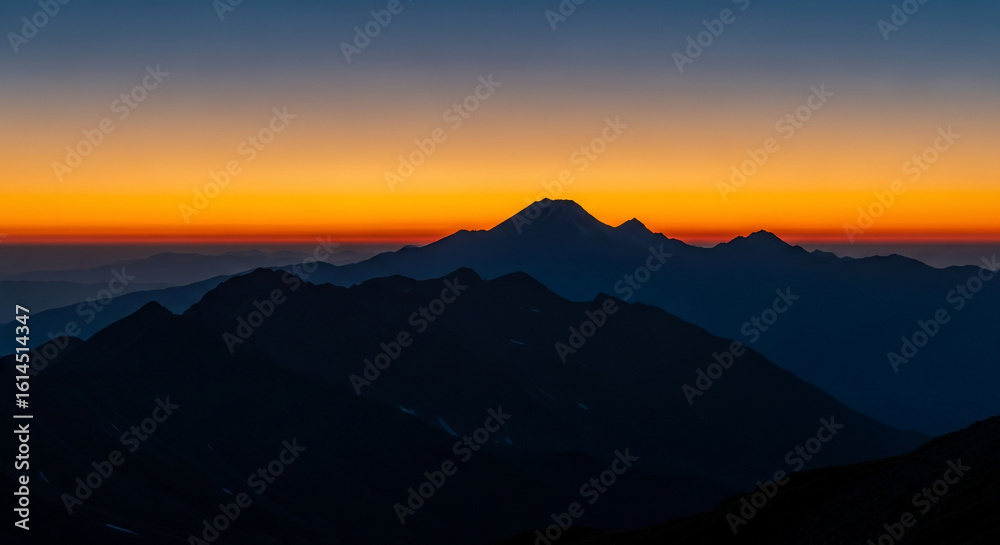 Fototapeta premium Vibrant Dawn Sky Over Silhouetted Mountain Peaks: Tranquil Alpine Landscape