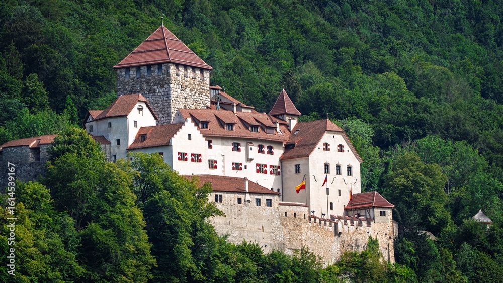 Fototapeta premium A majestic medieval castle sits on a hill, surrounded by a vibrant green forest. This stunning image is ideal for travel brochures, historical documentaries, or fantasy book covers.