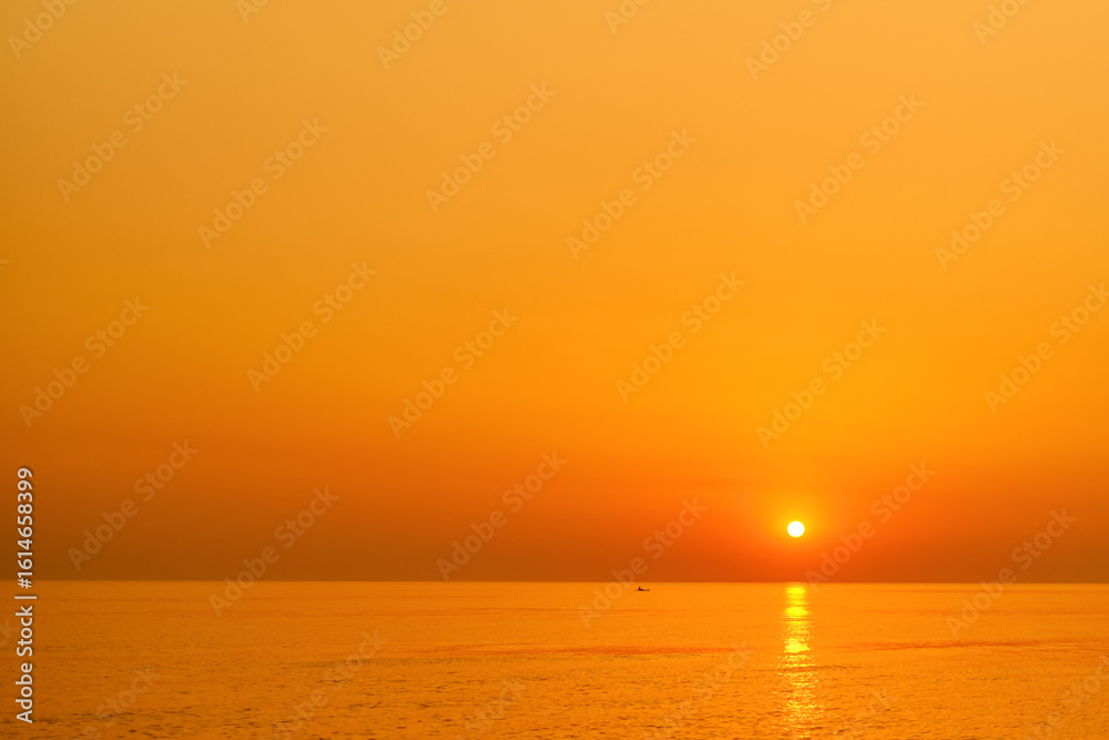 Fototapeta premium Beautiful calm sunset over the sea with golden hues of the sky in the smoke on the horizon, magnificent view and surreal view of the evening sea