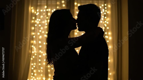 Silhouette of couple kissing in warm backlight, romantic sunset or fairy light scene, 4K