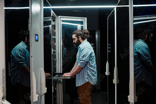IT expert working by servers standing in control room