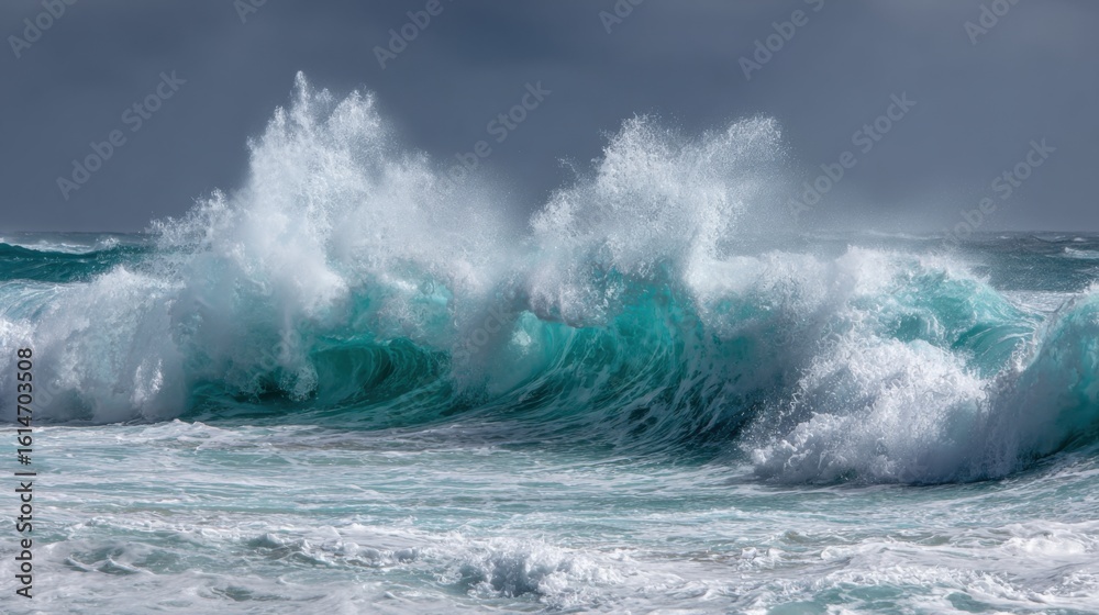 Obraz premium Turbulent waves rise and crash onto the sandy beach, creating white foam and splashes under a dark, cloudy sky in the late afternoon.