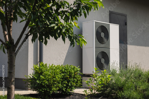 Papier peint Modern outdoor heat pump unit installed near a residential house wall, surrounde