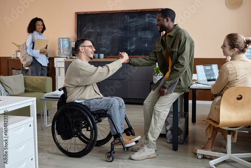 Happy businessman with disability shaking hands with colleague in office
