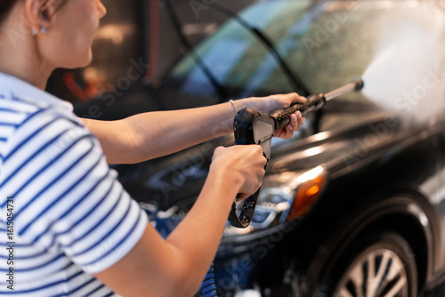 Foto Woman washing car with high pressure washer lance