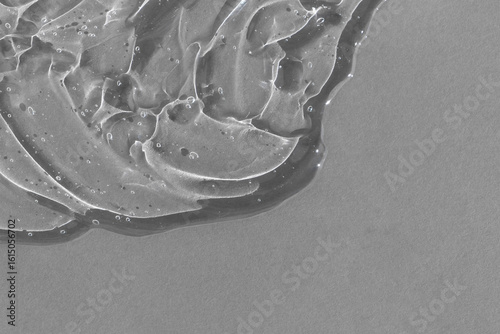 Transparent serum gel with hyaluronic acid for the face on a gray background. The texture of a cosmetic product with oxygen bubbles. Wellness and beauty concept.