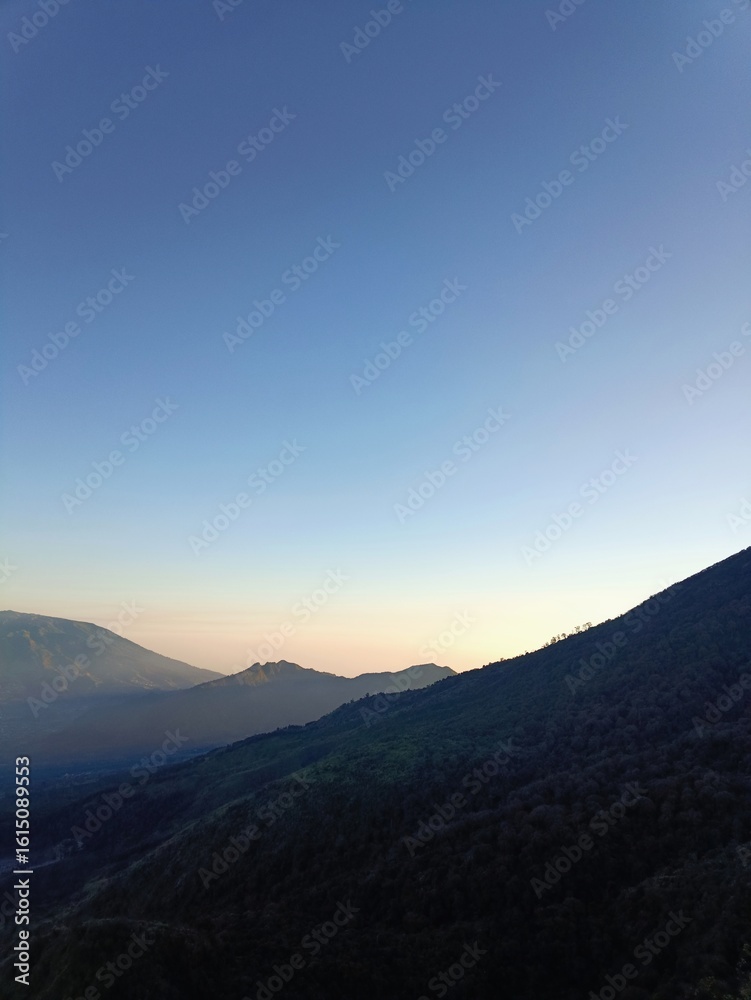 Obraz premium Sunrise Over Misty Hills and Green Valleys