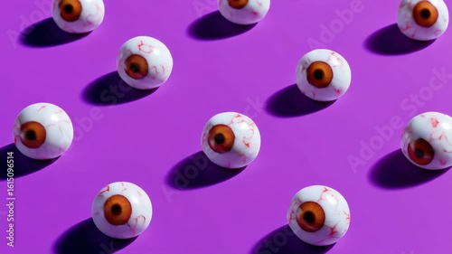 A row of eyeballs with red irises are on a purple background. The eyes are made of candy and are arranged in a pattern. The image has a playful and whimsical mood