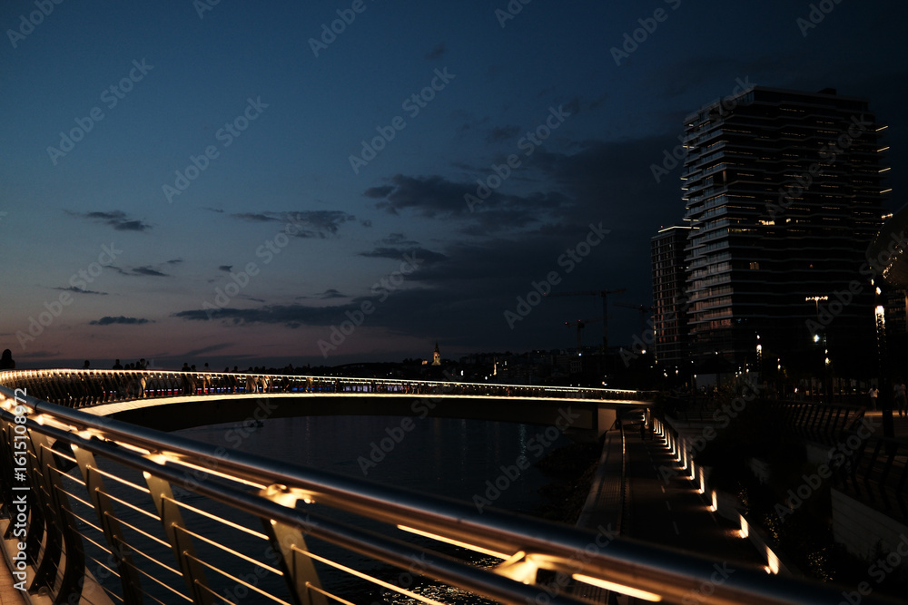 Night view of the Belgrade Waterfront promenade with modern high-rises, bike path, and dramatic sky. Quiet urban scene by Sava river. Night view of the Belgrade Waterfront promenade with modern high-rises, bike path, and dramatic sky. Quiet urban scene by Sava river.