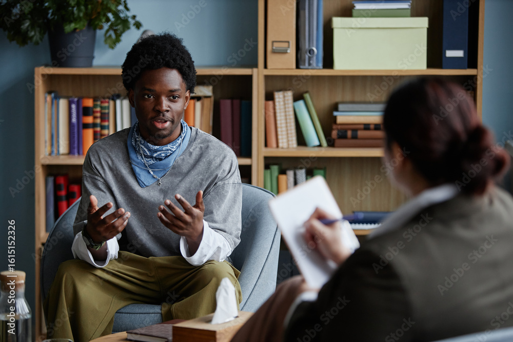 Φωτογραφία Black teenage boy sitting and talking with adult woman counselor during counseli