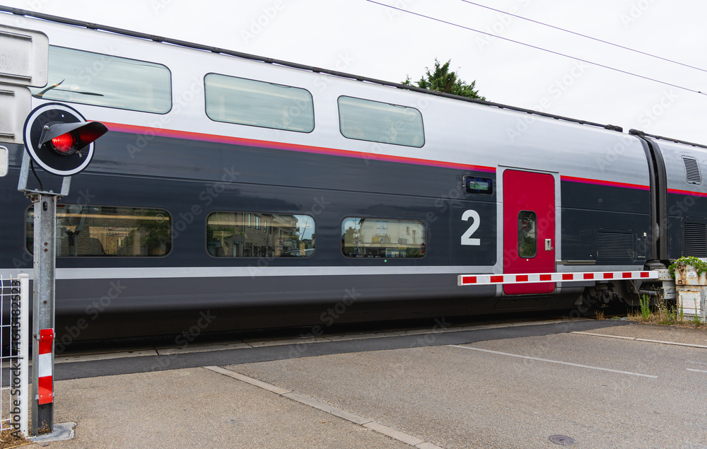 Fototapeta premium Train à deux niveaux circulant avec un signal d'arrêt visible rouge.