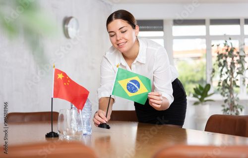 Photography Young woman setting up flags on table for international negotiations between chi