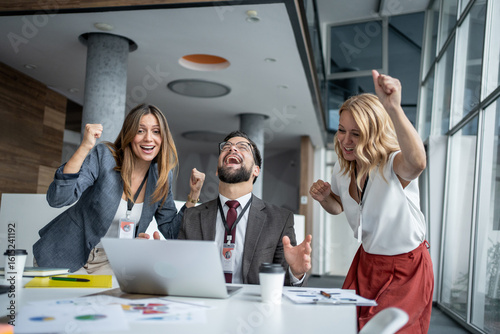 Tableau sur toile Excited business team celebrating success at work using laptop