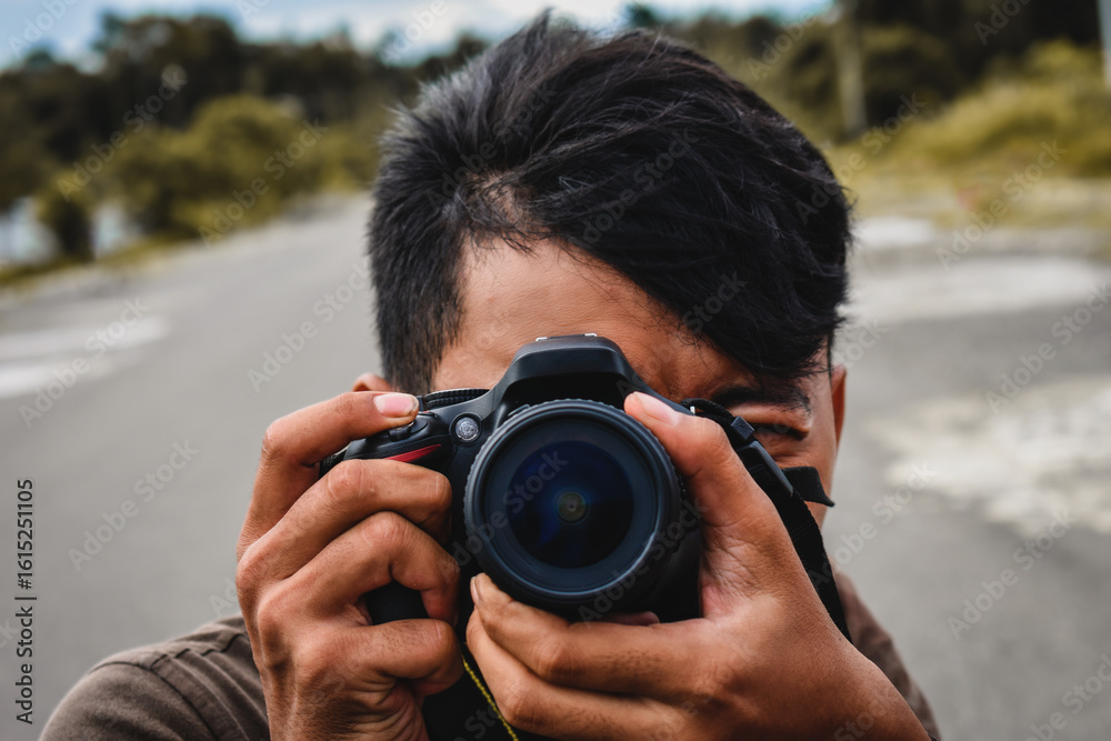 Obraz premium Man Taking Photo Outdoors with DSLR Camera