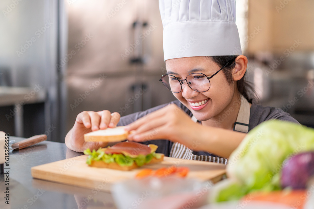 Smiling Young Female Chef Preparing a Sandwich in a Professional Kitchen Smiling Young Female Chef Preparing a Sandwich in a Professional Kitchen