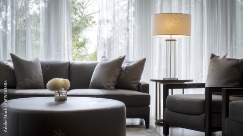 Elegant modern living room with grey leather ottoman, fabric sofa, matching cushions, beige lampshade floor lamp,