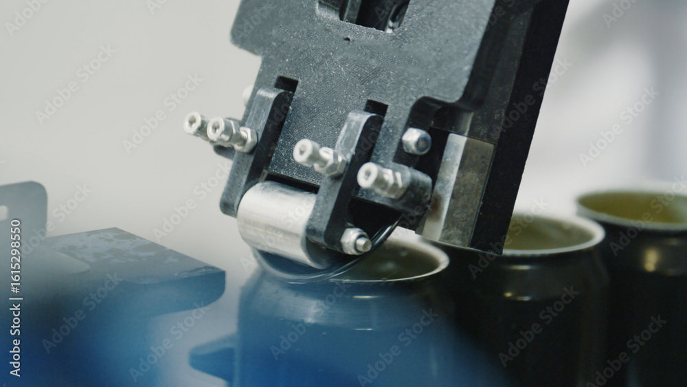 Fototapeta premium Automated industrial machinery applying tops to metal beverage containers, optimizing production in a modern factory setting, showcasing advanced manufacturing technology