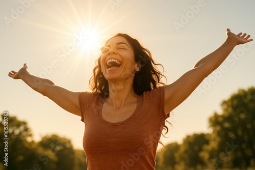 Joyful woman celebrating with arms outstretched against a sunny sky