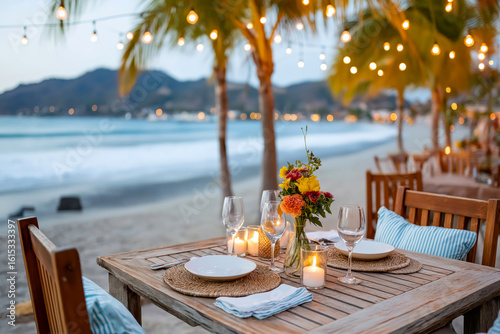 Beachside dining setup with elegant table  floral centerpiece  and glowing candles  surrounded by palm trees and ocean waves  creating a romantic atmosphere for evening meals