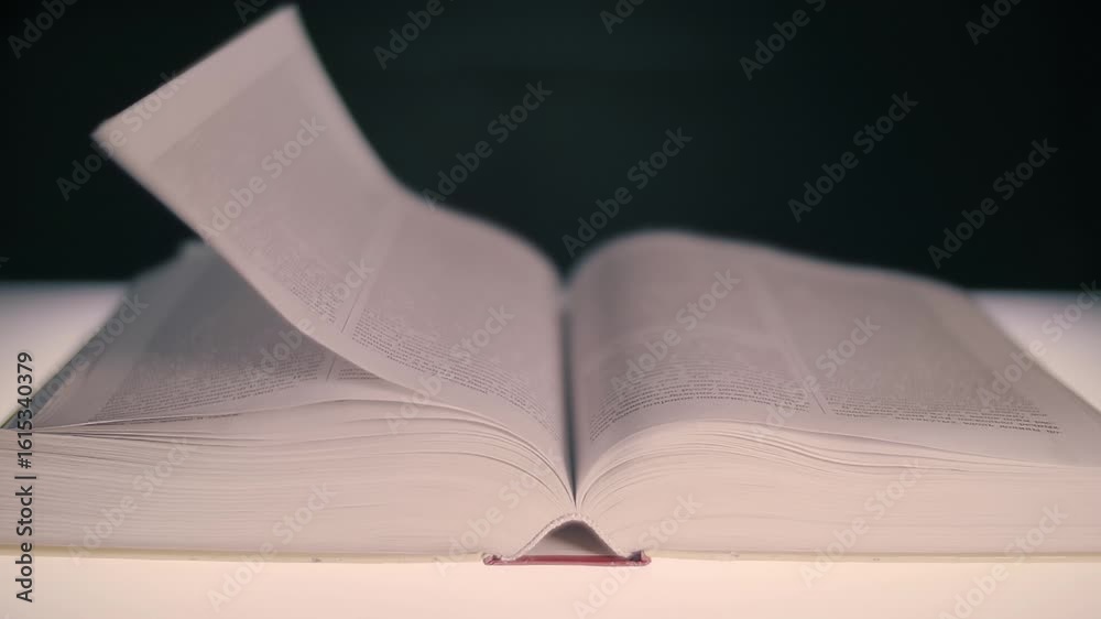 A thick book, open in the middle, which is exposed to a flow of air and ...