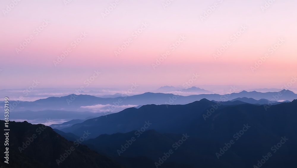 Fototapeta premium A scenic view of layered mountain ranges under a pastel colored sky at dusk or dawn with soft lighting