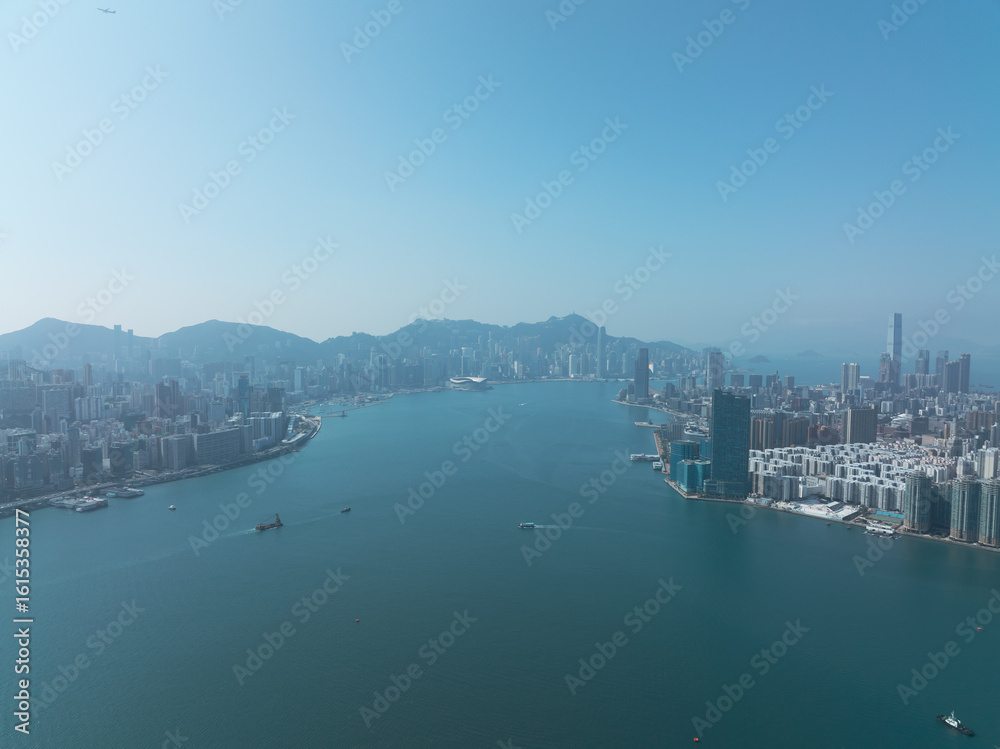 Naklejka premium Aerial view of central Hong Kong, China. Cityscape with skyscrapers lining the harbor under a clear sky. Urban scene showcasing the dense architecture and waterfront.