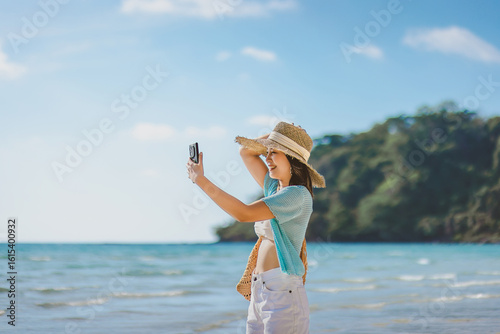 Happy asian traveler woman relax and use mobile phone for selfie on sea beach at day in Koh Kood Trat Thailand Travel summer holiday vacation concept