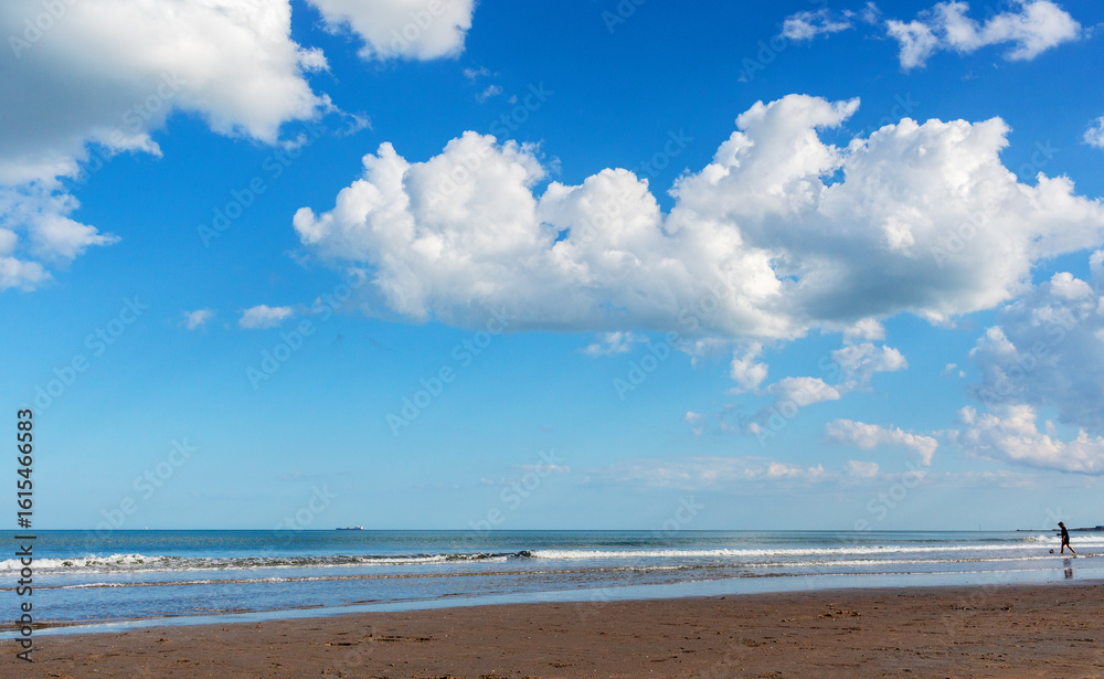 Scenic beach landscape with soft waves lapping at the shore under a bright blue sky filled with fluffy clouds, creating a serene and tranquil atmosphere for relaxation Scenic beach landscape with soft waves lapping at the shore under a bright blue sky filled with fluffy clouds, creating a serene and tranquil atmosphere for relaxation