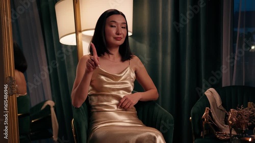 Confident Asian woman Chinese female at home looking at camera shaking finger no forbidden stop never not deny reject disagree negative gesture Korean Japanese lady in golden dress in evening style