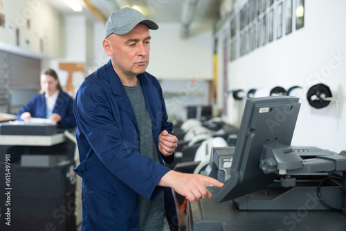 Papier peint Printing house employee works on modern printing equipment
